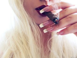 Blond girl with beautiful nails smokes the havana